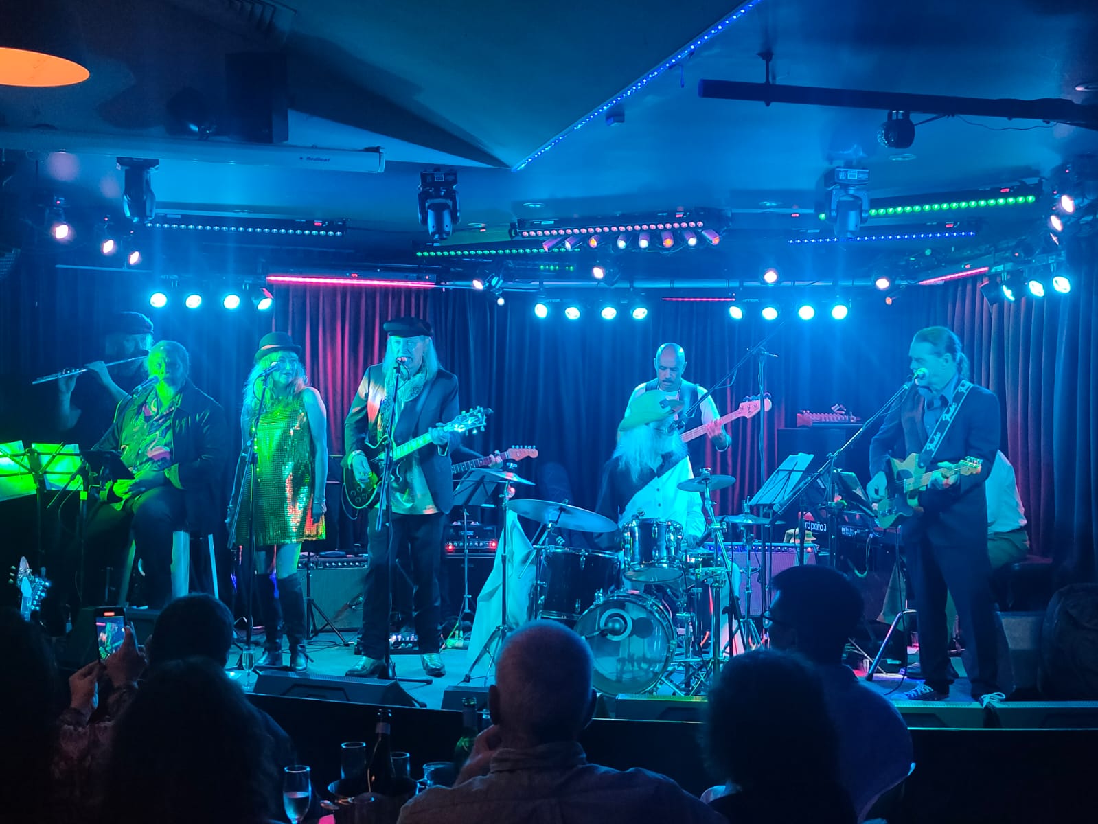 The full band on stage under blue and red lights at the Basement