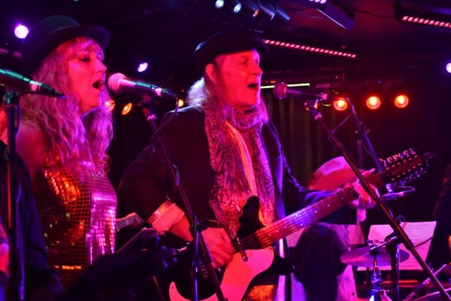 Billy on guitar sharing the mic under red stage lights
