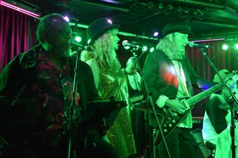Three singers at the mics under green stage light